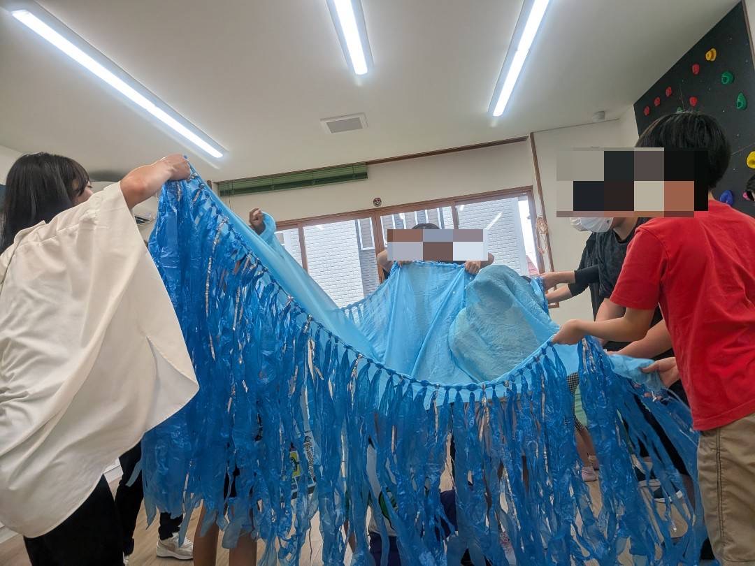 すずらんテープの海のグッズをみんなで持ち上げて盛り上がる様子